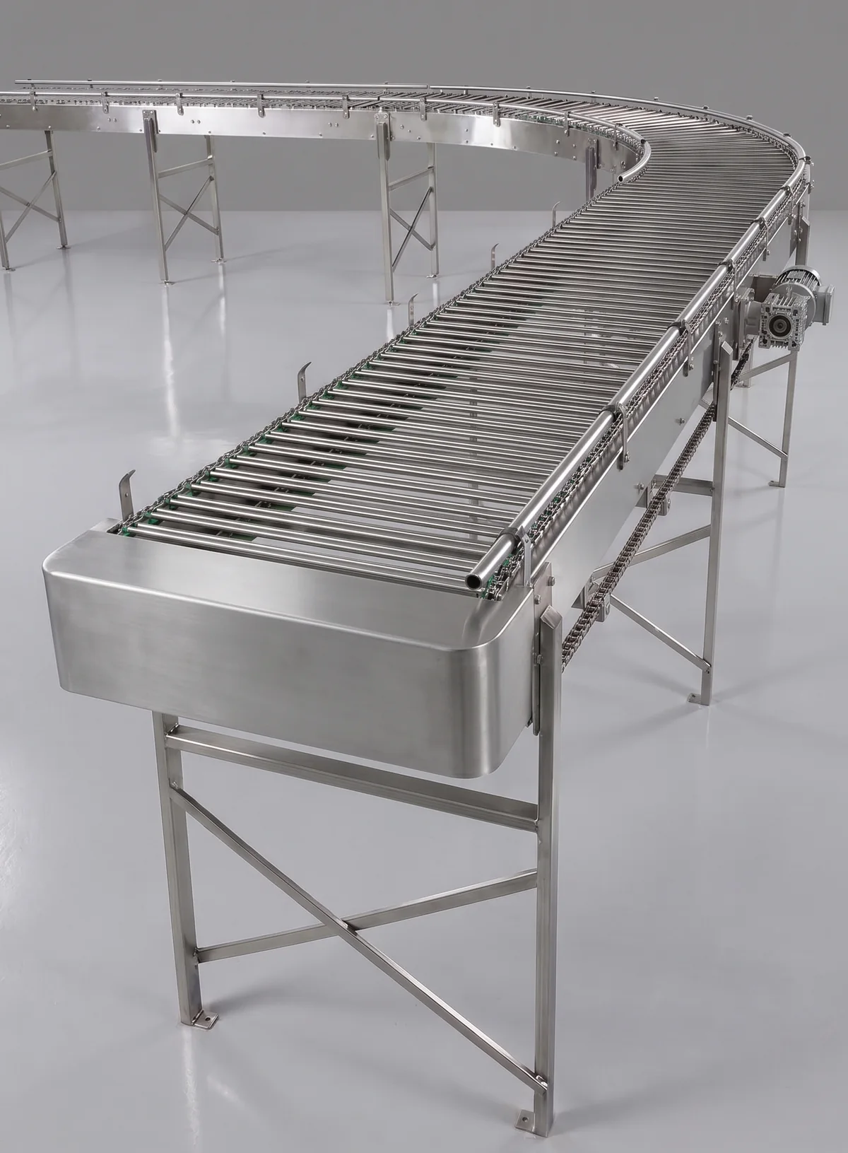 A curved stainless steel rod-top conveyor with an enclosed drive head, on a plain studio floor